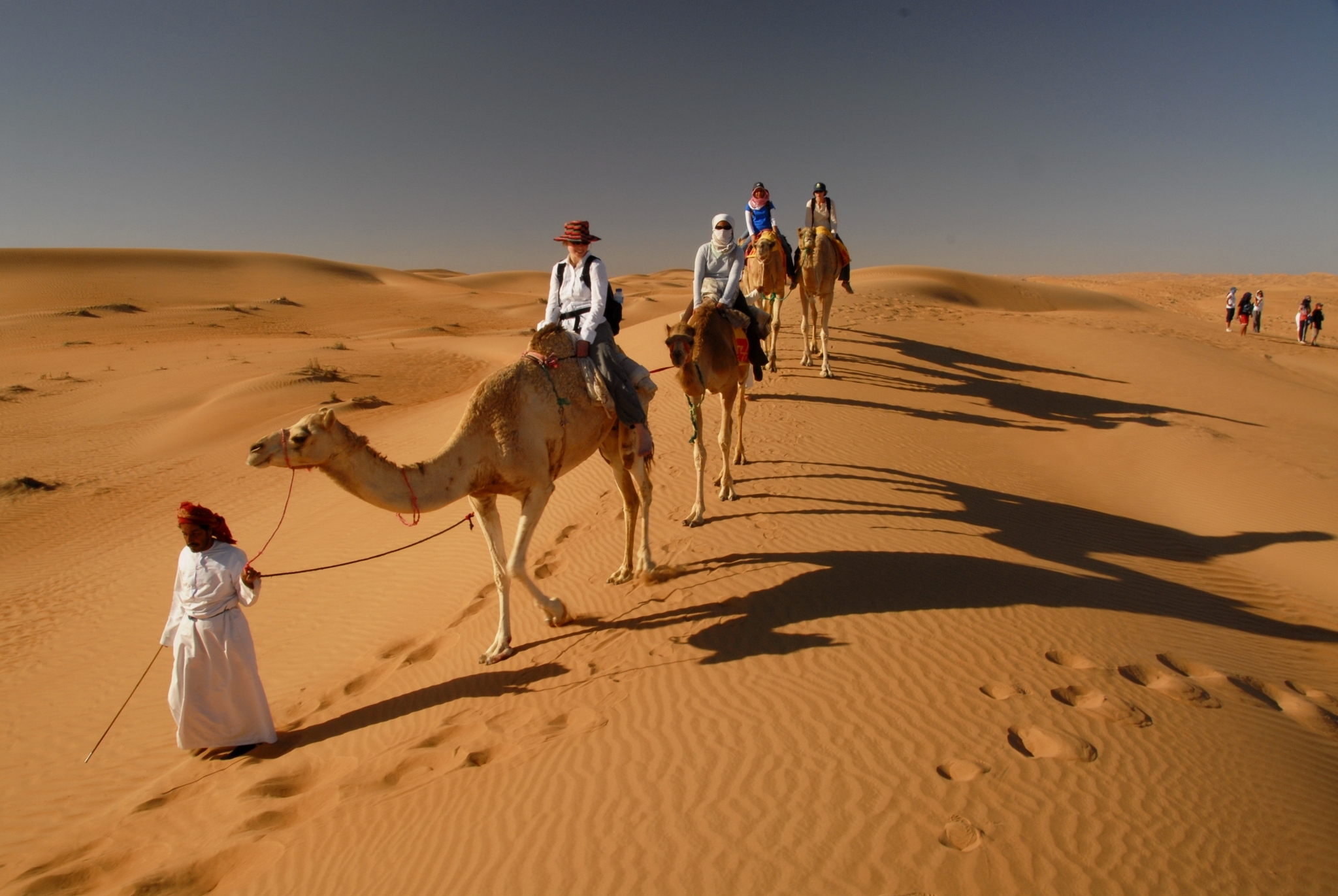 tourists riding camels at Wahiba sands